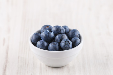 bowl with blueberries on a wooden background