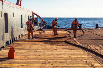 Anchor-handling Tug Supply AHTS vessel crew preparing vessel for static tow tanker lifting. Ocean...