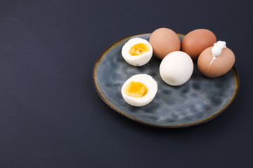 Boiled eggs on a plate. Black background. Place for text. Protein and nutrition