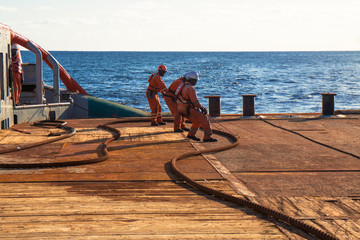 Anchor-handling Tug Supply AHTS vessel crew preparing vessel for static tow tanker lifting. Ocean...