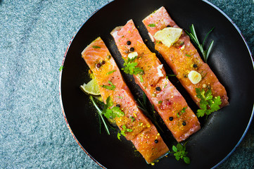 Salmon slices with cooking ingredients on a pan