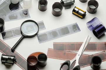 Fototapeta na wymiar 35mm photographic film, magnifying glass and scissors on white background