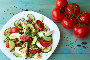 Vegetable salad with egg and a branch of tomatoes on a blue wooden background.