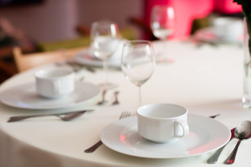 Tableware before the family party. Cutlery and plates on the table with a tablecloth.