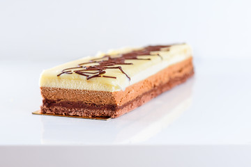 Delicious chocolate cake on white background, closeup. Three layers of different chocolate filling.TriColad cake-Triple color  Mousse. Selective focus.