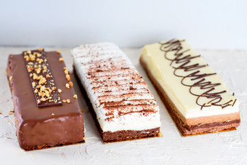 Beautiful Delicious dessert cheesecakes and chocolate cake  on a white trendy background. Group of three different types of sweet for jewish holiday Shavuot.