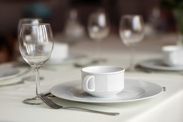 Tableware before the family party. Cutlery and plates on the table with a tablecloth.