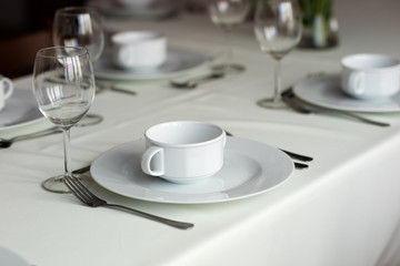 Tableware before the family party. Cutlery and plates on the table with a tablecloth.