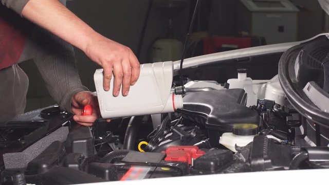 Pouring oil to car engine, close up.