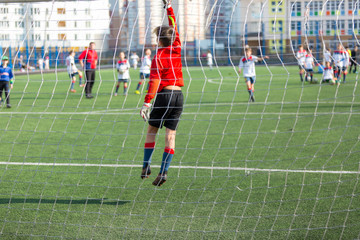 kid football goalkeeper jumps and catches a ball while training of his team on the stadium