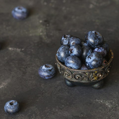 Blueberry fruit berries in a vintage metal bowl on dark background