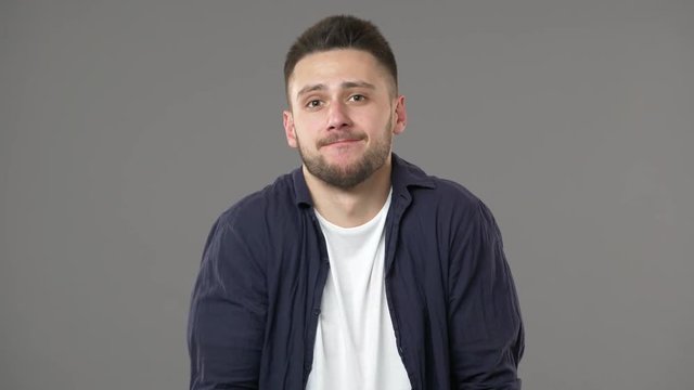 Portrait of perplexed man in casual clothing shrugging and expressing misunderstanding with throwing up hands, isolated over gray background. Concept of emotions