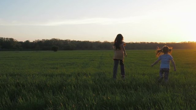 Children in the field at sunset. Little girls are running at sunset.