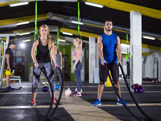 sports couple doing battle ropes crossfitness exercise