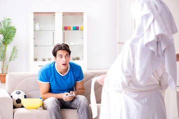 Obraz premium Young wife is trying to seduce husband from watching football an