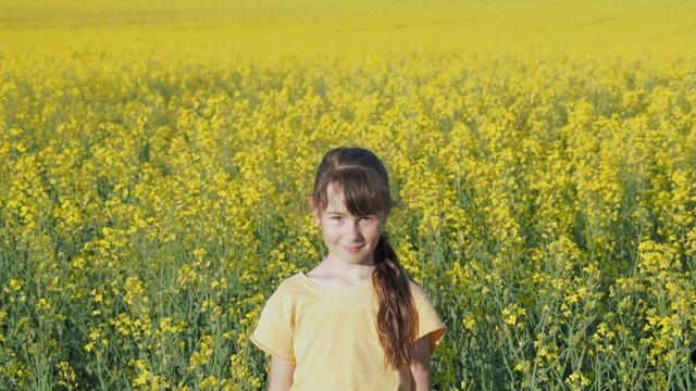 Child in the field. A little girl is spinning in a field of yellow flowers.Daughter of a farmer in a rapeseed field.