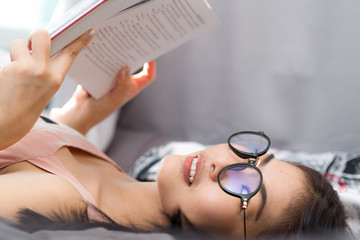 Student asian women reading book on cozy bed condominium room