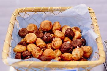 Mini eclairs balls made by white flour and chocolate flour inside basket.
