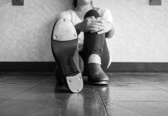 Black and white version of Tap dancer lounging and showing her tap shoes 