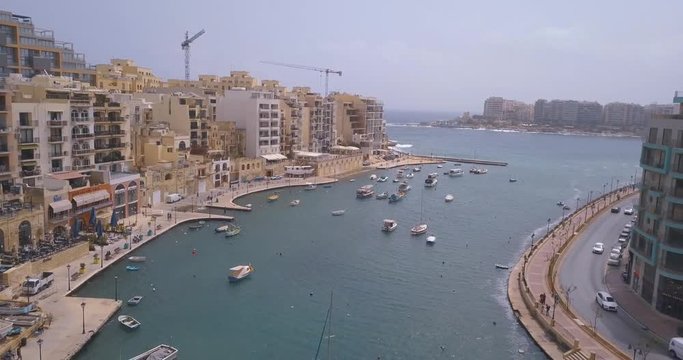 Aerial view over Spinola Bay with Traditional maltese Luzzu fishing boats and beautiful view from above with St Julian, Sliema and Valetta cities.
