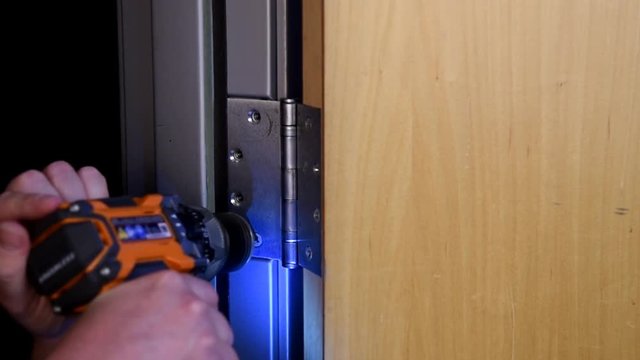 Male model uses a battery powered drill to install a door hinge