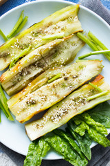 Eggplant backed and roasted in oven or on open fire with sesame seeds, spices, pepper, garlic, spinach and salad leaves. Raw, vegan, vegetarian healthy food concept.