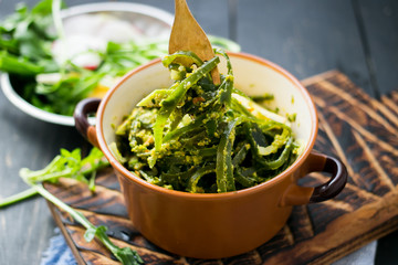 Seaweed salad twirls around fork with lemon, oil, garlic, spices, chili pepper, sesame seeds. Asian japanese chuka. Organic natural product. Raw, vegan, vegetarian food
