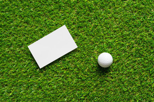 White paper background and golf ball on green grass of golf course background.