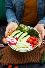 Buddha Bowl with fresh vegetables. Cucumbers, tomatoes, radish, cabbage, avocado, almonds. Top view. Organic natural products. Raw, vegan, vegetarian healthy food