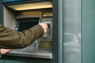 The tourist withdraws money from the ATM for further travel. Grabs a card from the ATM. Finance, credit card, withdrawal of money.