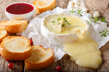 Freshly baked Camembert cheese with garlic, thyme served with toast and berry sauce close-up on the table. horizontal