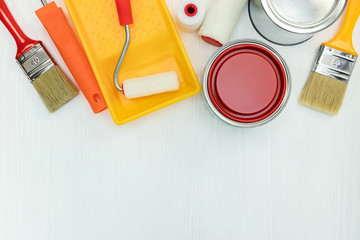 painting tools on white wooden background. paint cans, brushes and rollers with paint tray. flat view