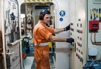 Marine engineer officer controlling vessel engines and propulsion in engine control room ECR. Ship...