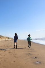 Naklejka premium 砂浜を走る子どもたち