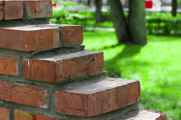 Part of wall made from red bricks against the background of green grass