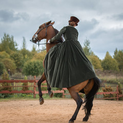 Lady riding a horse in a historical costume of the 19th century