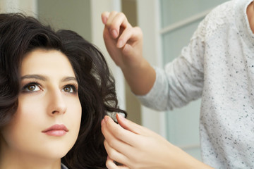 Fototapeta premium Closeup view of the hand and comb of a hairstylist combing a new hairstyle on a customer head in hair salon.