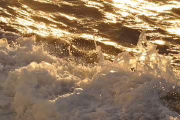Splashing and foaming water, reflecting glaring light of setting sun