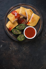 Rustic wooden serving board with sliced chicken cordon bleu, view from above on a dark brown stone background, vertical shot with space