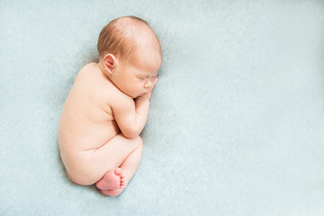 Naked newborn baby sleeping on a light background. Copy space