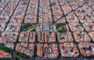 Fototapeta premium Widok z lotu ptaka na dzielnicę mieszkaniową Barcelona Eixample i Sagrada Familia wewnątrz typowych placów miejskich, Hiszpania. Miękkie światło późnego popołudnia