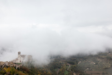 View of St. Francis papal church in Assisi (Umbria, Italy) in the middle of lifting morning fog