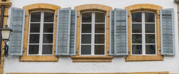 Fototapeta na wymiar close up view of three windowls with wooden window shutters in blue