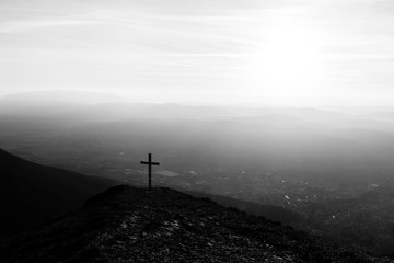 Cross on top of Mt. Serrasanta (Umbria, Italy), with sun low on the horizon