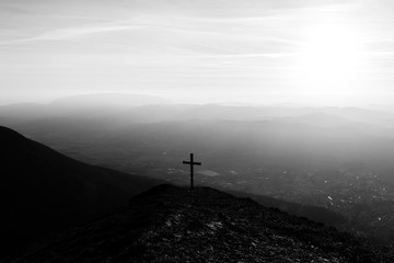 Cross on top of Mt. Serrasanta (Umbria, Italy), with sun low on the horizon