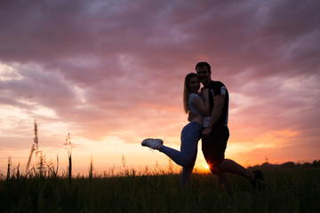 Silhouette of a young couple on sunset sky