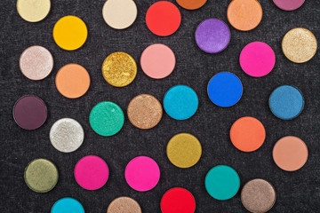 set of shimmer and matt multicolored round shaped eye shadows lying on a black background. concept of professional make up products