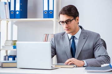 Naklejka premium Young handsome businessman employee working in office at desk
