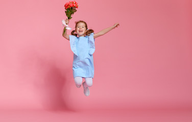 funny child girl runs and jumps with bouquet of flowers on colored background