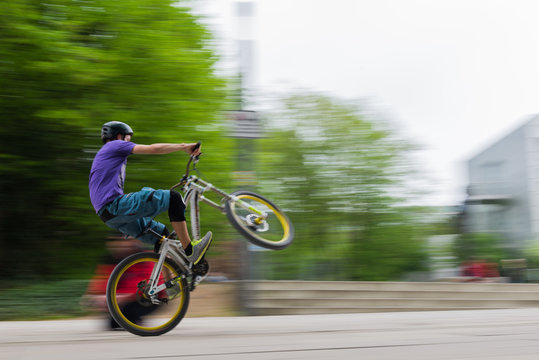 Jugendlicher Mountainbike-Fahrer mit angehobenem Vorderrad in der Fußgängerzone
